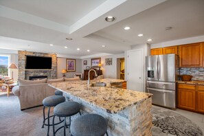 A modern kitchen with granite countertops, stainless steel appliances, and wooden cabinets. - Ski-in/Out, Walk to Base Area - Torian Plum - Pool& Hot Tubs (Steamboat Springs)