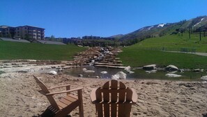 Relax by the serene river, where stepping stones lead to a tranquil spot with two Adirondack chairs.