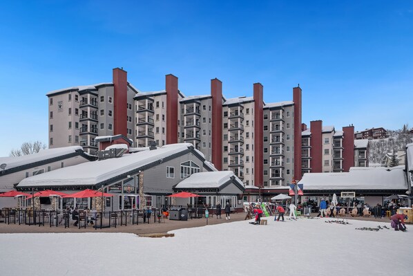 Un hotel con varios pisos, balcones y un techo cubierto de nieve.