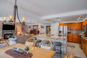 A modern kitchen with a central island, built-in appliances, and a stone fireplace. - Ski-in/Out, Walk to Base Area - Torian Plum - Pool& Hot Tubs (Steamboat Springs)