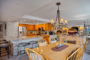 A spacious kitchen with wooden cabinets, a granite countertop, and a central island with bar stools. - Ski-in/Out, Walk to Base Area - Torian Plum - Pool& Hot Tubs (Steamboat Springs)