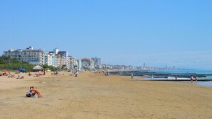 A beach with buildings in the background, people relaxing, and a clear sky. - Belvilla by OYO Appartamento N1 (Venice)