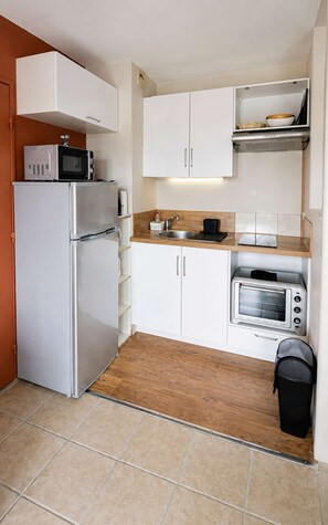 A compact kitchen with a refrigerator, microwave, toaster oven, and a sink.