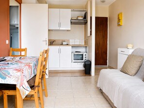 A compact living space with a kitchenette, a dining area with a table and chairs, and a bed.