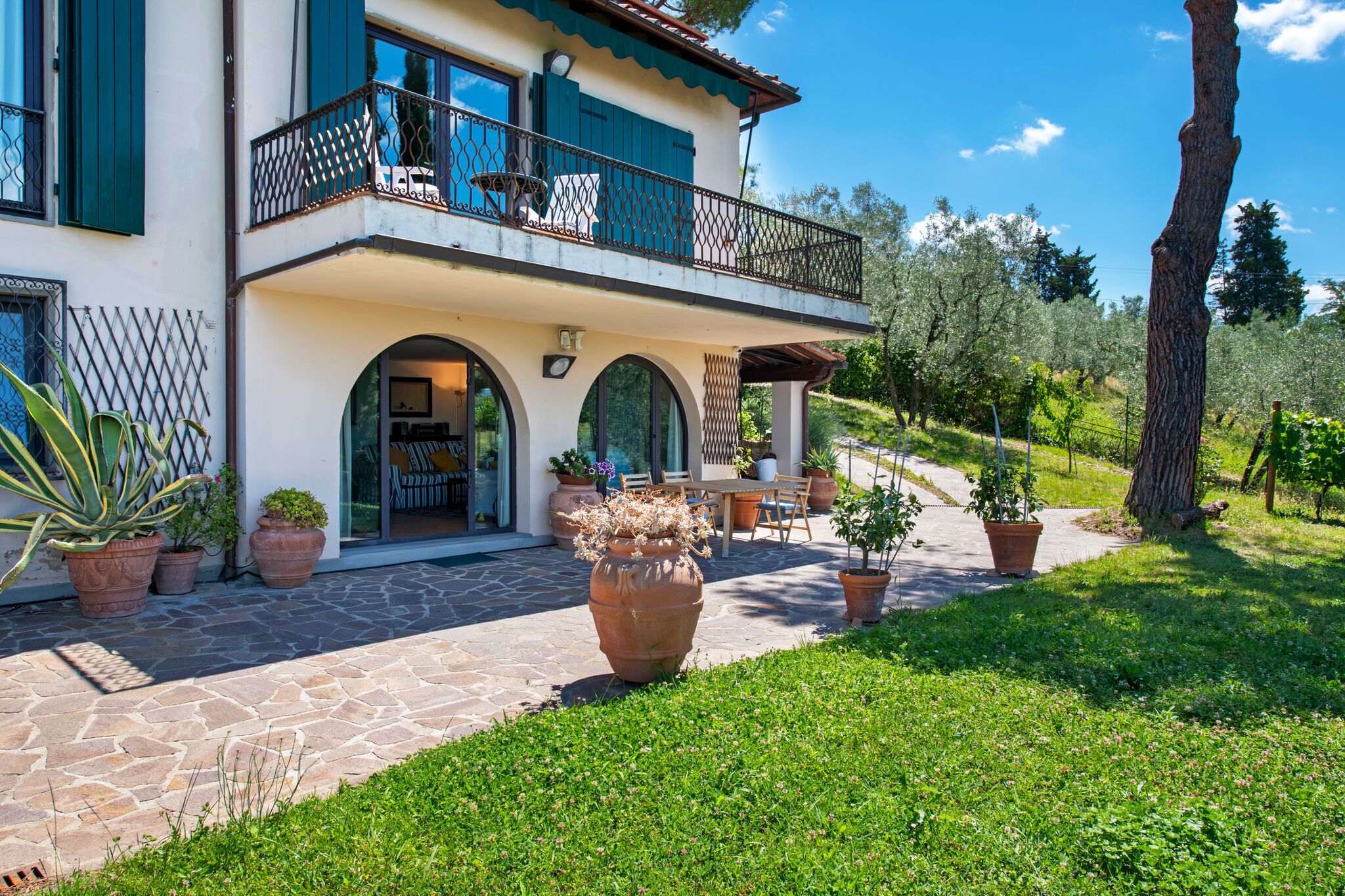 Une maison à deux étages avec un balcon, un chemin en pierre et des plantes en pot.