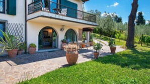 Una casa de dos pisos con balcón, sendero de piedra y plantas en macetas.