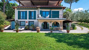 Una casa de dos pisos con balcón, mobiliario exterior y macetas con plantas.