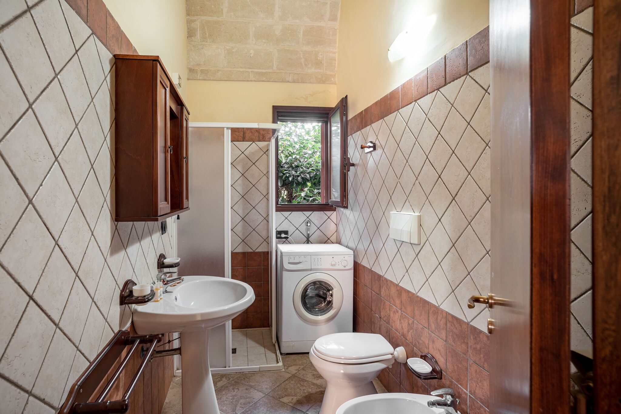 Un baño pequeño con lavamanos, inodoro y lavadora.