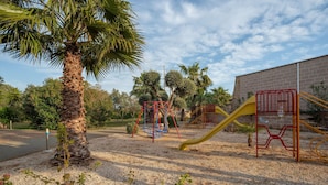 Ein Spielplatz mit Schaukeln, einer Rutsche und einer Kletterkonstruktion.