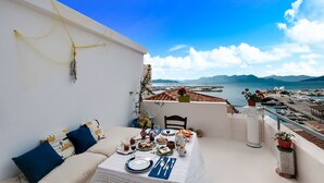 A balcony with a table set for dining, overlooking a marina with boats and a clear blue sky. - Holiday Home in Aegina Island (Aegina Island)