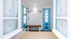 A hallway with a bench, a door with frosted glass panels, and a hanging light fixture. - Holiday Home in Aegina Island (Aegina Island)