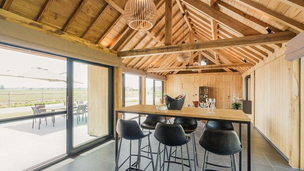 Una cocina moderna con techo de madera, ventanas amplias y una barra con taburetes.