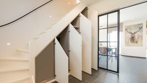 Una escalera moderna con puertas abiertas que dan a una habitación con un gran ventanal y una pintura de un ciervo.