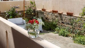 Un balcon avec une chaise blanche, un parasol blanc et des plantes en pot.