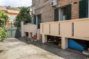 Une ruelle étroite avec un immeuble de couleur beige, des volets verts et une porte bleue.