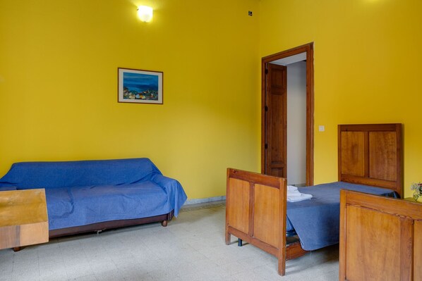 A room with a yellow wall, a blue sofa, a wooden bed, and a wooden wardrobe.
