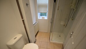 Un baño pequeño con inodoro, ventana y cabina de ducha de vidrio.