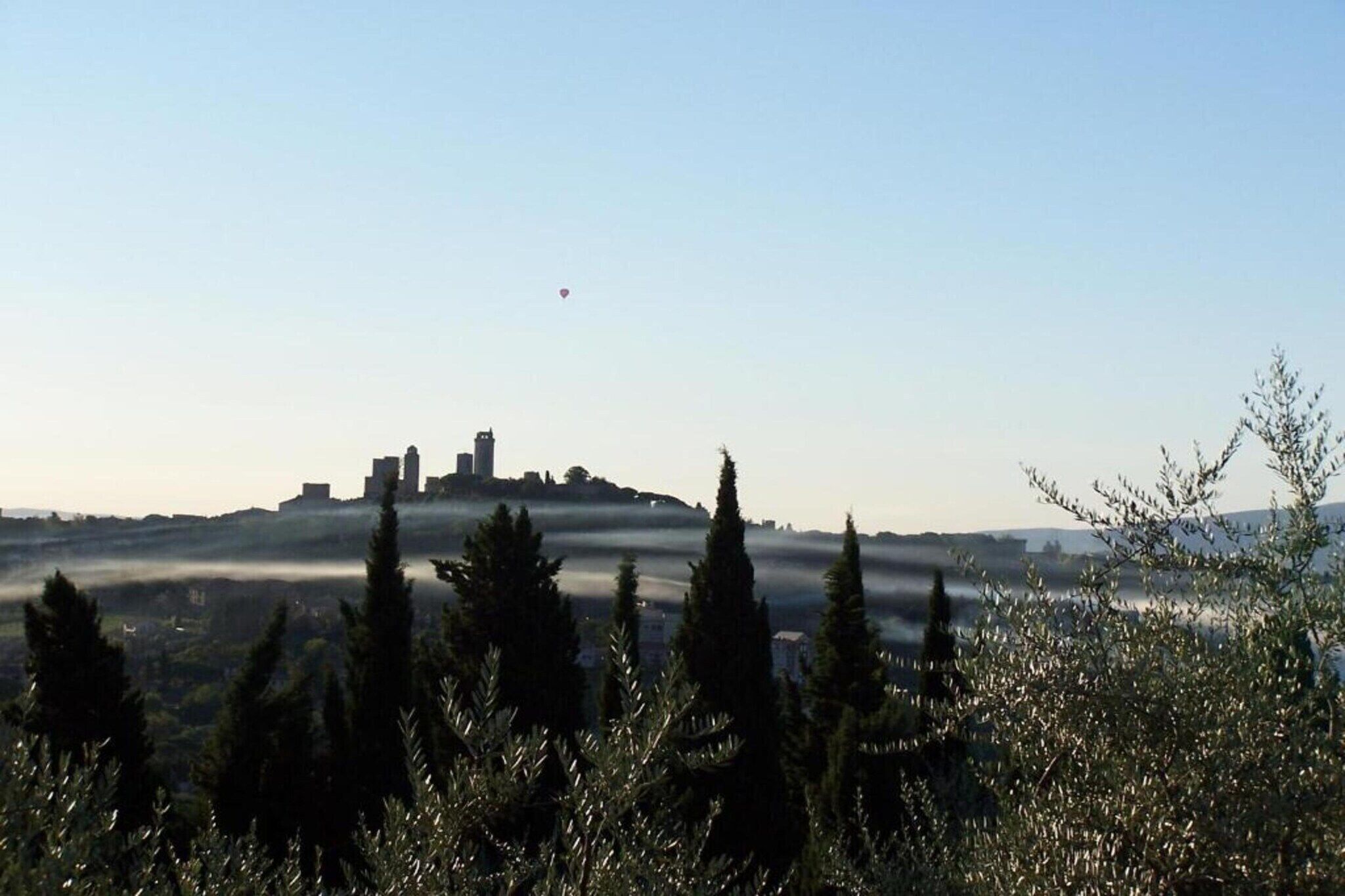 A cityscape with a prominent hill and a hot air balloon in the sky.