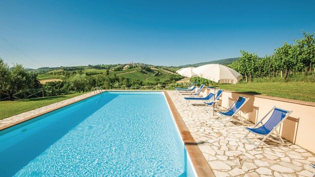 Ein Swimmingpool mit Liegestühlen und Blick auf Weinberge.