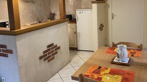 A kitchen with a wooden countertop, a white refrigerator, and a dining area with a table set for two.