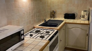 A compact kitchen with a gas stove, a microwave, a sink, and a coffee maker.