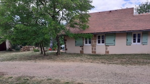 A building with a tiled roof, a stone facade, and green shutters.