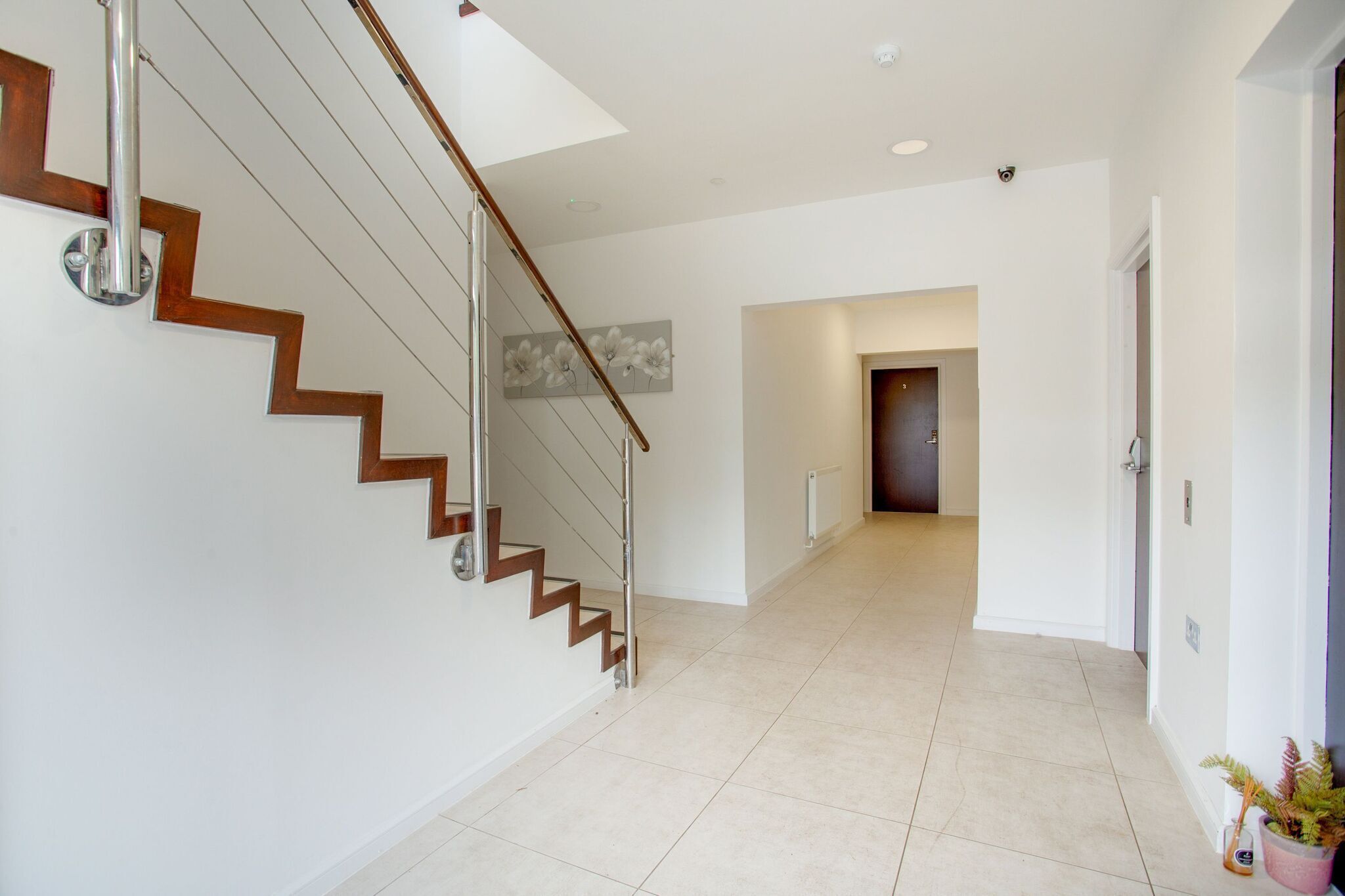 Un interior moderno con una escalera, un pasillo y una puerta al final.