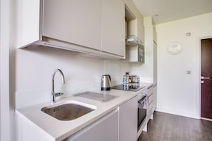 Una cocina moderna con un lavamanos de acero inoxidable, un hervidor y una tostadora en la encimera.