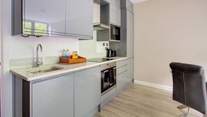 Une cuisine moderne dotée d’un four encastré, d’un four à micro-ondes et d’une grande fenêtre au-dessus de l’évier.