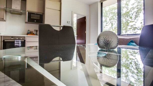 Una cocina moderna con una mesa de comedor de vidrio, un objeto esférico decorativo y vistas al exterior.