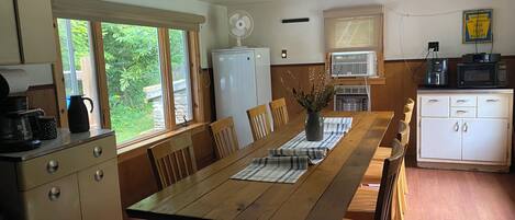 Eine Küche mit Holztisch, Stühlen, einem Kühlschrank, einer Mikrowelle und einem Deckenventilator.
