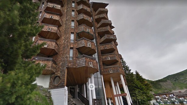 Een meerlaags gebouw met een uniek architectonisch ontwerp, met balkons en een trap die naar de ingang leidt.