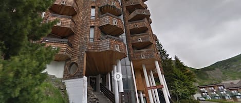 A multi-story building with a unique architectural design, featuring balconies and a staircase leading to the entrance.