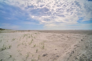 Escape to a serene beachside haven with endless sandy dunes and sparse vegetation.