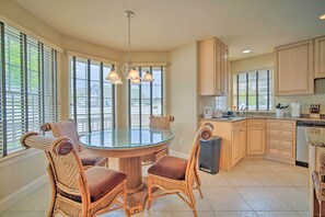 Kitchen with central island, wicker chairs, and stainless steel range hood.