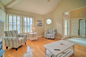 Relax in this inviting living room with a high ceiling, large windows, and comfortable seating areas.