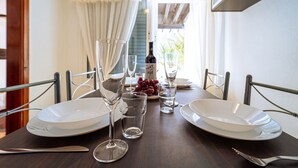 A dining table set with plates, glasses, and cutlery, with a bottle and grapes on the table.