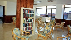 Una biblioteca con estanterías y sillones de mimbre.