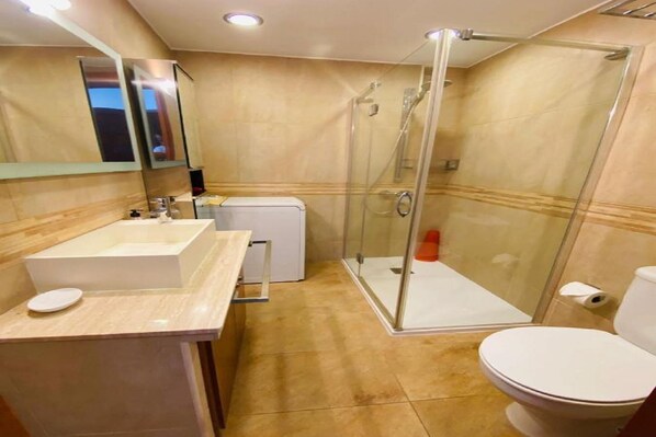 A modern bathroom with a glass-enclosed shower, a white sink, and a toilet.