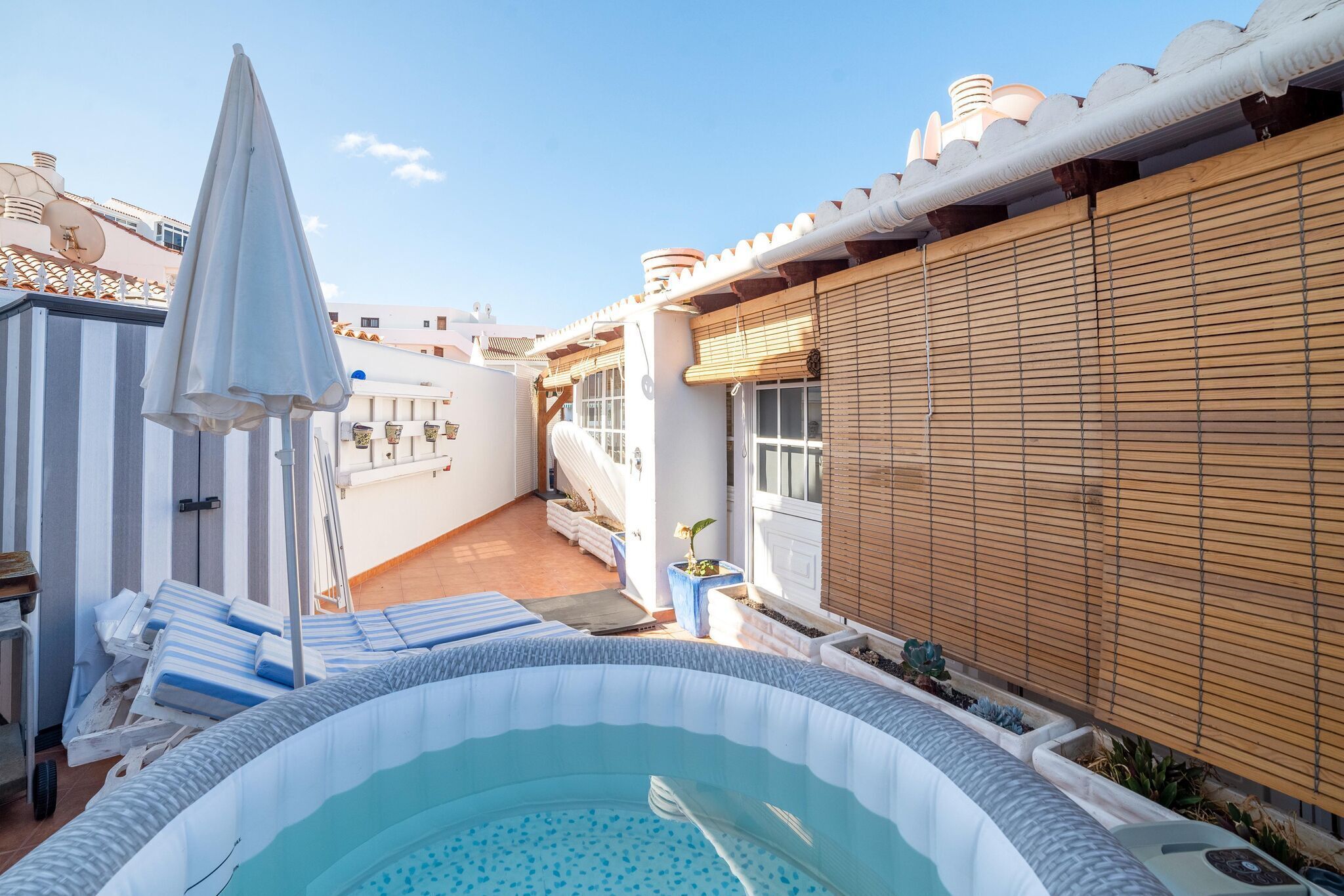 A pool area with lounge chairs and a sun umbrella.