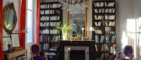 A cozy library with bookshelves, a fireplace, and a chandelier.