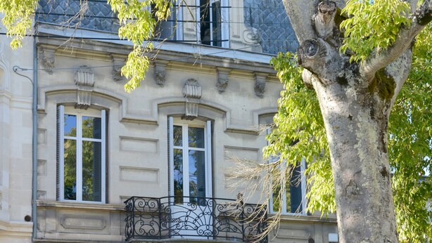 Un edificio histórico con fachada simétrica, ventanas amplias y una entrada central.