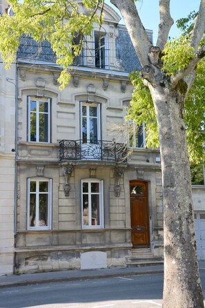 Un bâtiment historique à la façade symétrique, doté de grandes fenêtres et d’une entrée centrale.
