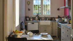 Cocina compacta con mesa, sillas, fregadero y ventana con vistas a zonas verdes.