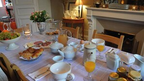 Una mesa de desayuno servida con diferentes platos, como cruasanes, fruta y bebidas.