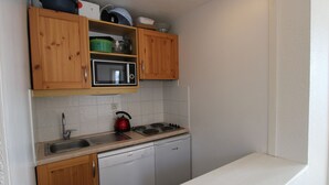 A compact kitchen with wooden cabinets, a microwave, a kettle, a dishwasher, and a sink. - Avoriaz - 2-room Apt, 6 pers, village view, WiFi (Avoriaz)