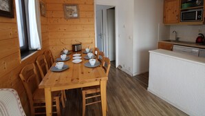 A wooden dining table with chairs, a kitchen area with a microwave, and a white countertop. - Avoriaz - 2-room Apt, 6 pers, village view, WiFi (Avoriaz)