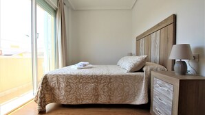 A neatly made bed with a patterned bedspread, a wooden headboard, and a bedside lamp.