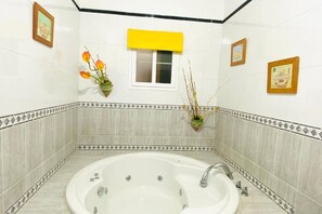 Ein Badezimmer mit einer Badewanne, einem Fenster mit gelbem Rollo und gerahmten Bildern an den Wänden.
