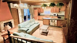 Una sala de estar con sofá, mesa de centro y chimenea. Cuenta con una zona de cocina con armarios de madera y microondas.